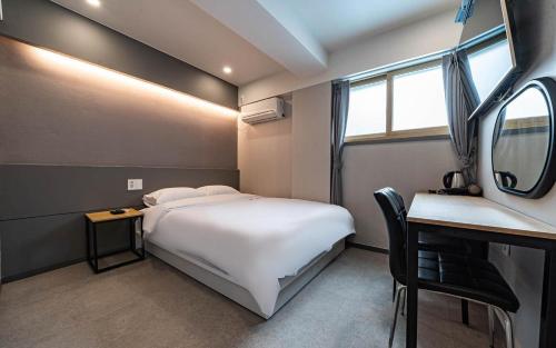 a bedroom with a bed and a table and a mirror at Lime Hotel in Busan