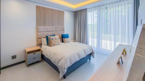 a bedroom with a bed and a large window at The Pearl Ballito in Ballito