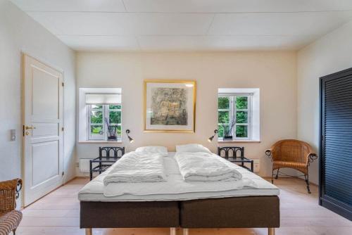 a bed in a room with two chairs and two windows at HS025-Outrup-Strandvejen-31-B in Henne