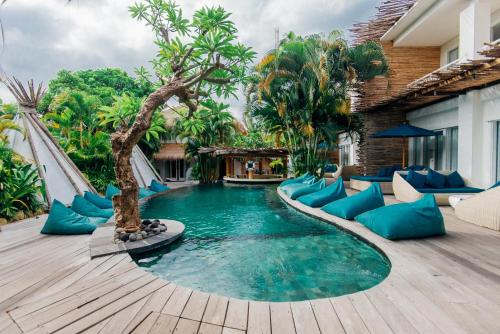 a swimming pool with blue pillows on a wooden deck at Kima Surf Camp Bali Seminyak in Seminyak