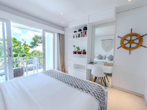 a white bedroom with a bed and a desk at Kima Surf Camp Bali Seminyak in Seminyak