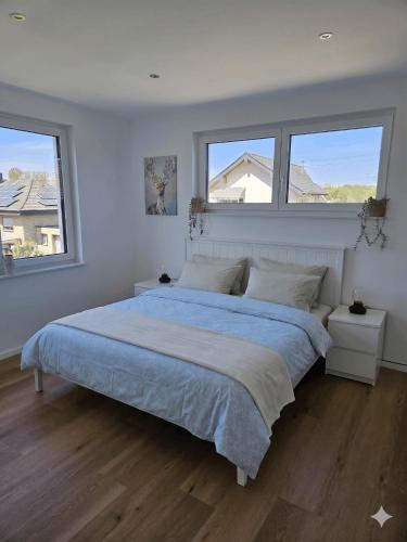 a bedroom with a large bed and two windows at Ferienwohnungen im Neubau in Ringen