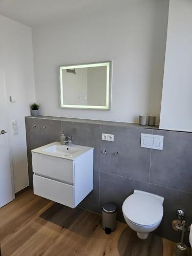 a bathroom with a white toilet and a sink at Ferienwohnungen im Neubau in Ringen