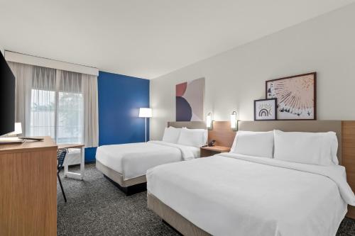a hotel room with two beds and a desk at Spark By Hilton Missouri City in Missouri City
