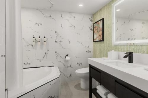 a white bathroom with a tub and a sink and a toilet at Le Parc Gatineau, Tapestry Collection by Hilton in Gatineau