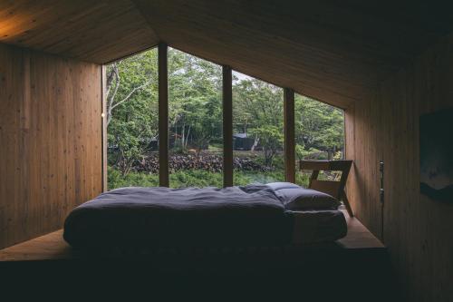a bed in a room with a large window at Earthboat Nasu - Glamping Cabin with Private Wood-Fired Sauna & Onsen, Pet-Friendly & Cage-Free in Nasu