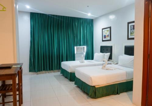 two beds in a room with green curtains at Ace Penzionne by Hiverooms in Pajo