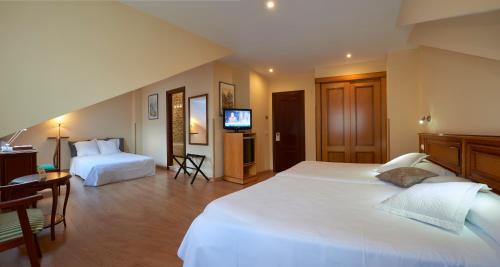 a large bedroom with two beds and a television at Hotel y Casona El Carmen in Perlora