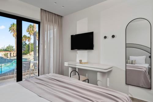 a hotel room with a bed and a desk and a tv at Atlantica Thalassa Hotel in Kos