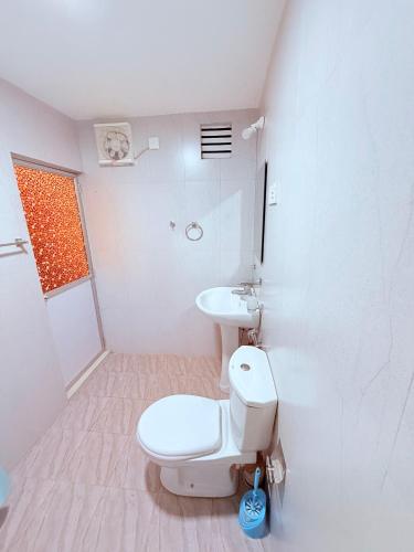 a white bathroom with a toilet and a sink at Thalpe Gedara Villa in Talpe