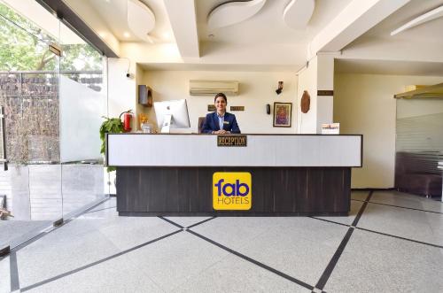 a woman standing at a reception desk in a lobby at FabHotel Harsh Paradise - Malviya Nagar in Jaipur