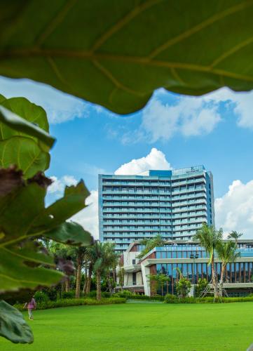 a tall building in front of a green field at Renaissance Haikou Hotel in Haikou