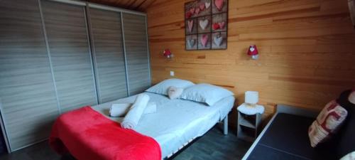 a small bed in a room with a red couch at Le petit chalet des Vosges proche Gerardmer in Corcieux