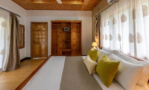 a large white bed in a room with windows at Maison Ed-Elle in La Digue