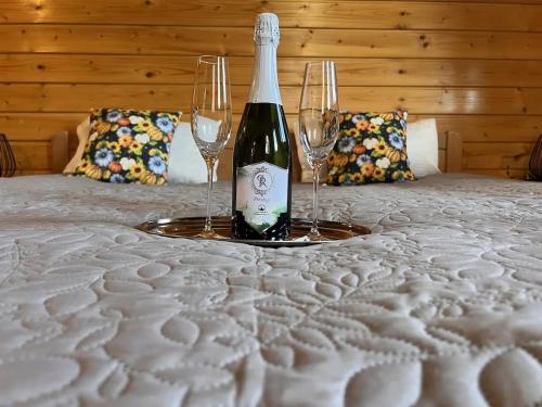 a bottle of wine and two wine glasses on a bed at Petőfi 35 Vendégház in Sirok