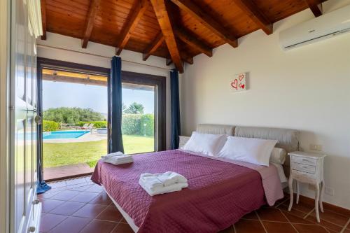 a bedroom with a bed and a large window at Villa Glory piscina privata in Cuile Pazzoni