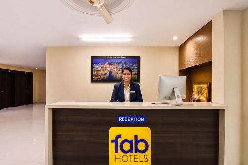 a woman standing at a reception desk in a hotel lobby at FabHotel Blue Inn I in Vagholi