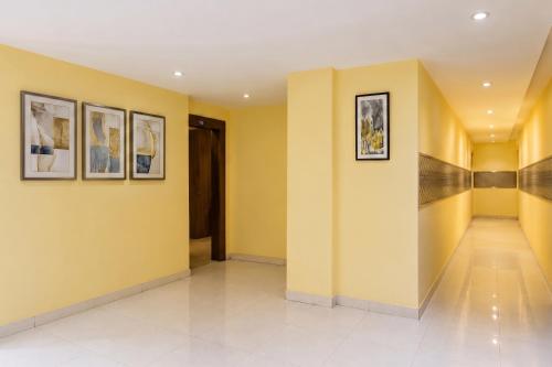 a hallway with yellow walls and pictures on the walls at FabHotel Blue Inn I in Vagholi