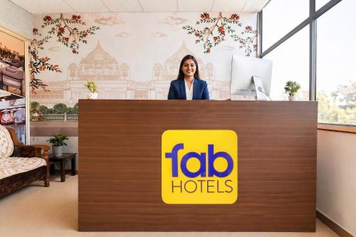 a woman stands behind a reception desk in a frito lay office at FabHotel Shivalika in Jaipur