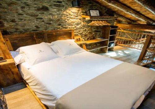 a large white bed in a room with a stone wall at Casa Rural Mariola in Ordino