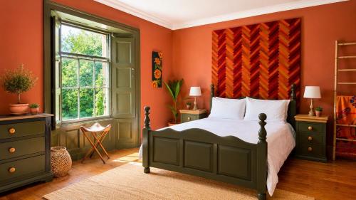 a bedroom with a bed with an orange wall at Beachborough Country House in Barnstaple