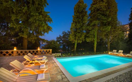a swimming pool with chaise lounge chairs and a swimming pool at Apartments Atlanta in Lovran