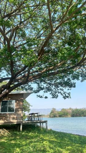 a cabin with a picnic table next to a lake at บ้านสวนริมอ่าง in Phayao