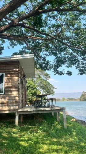 a house with a picnic table next to a lake at บ้านสวนริมอ่าง in Phayao