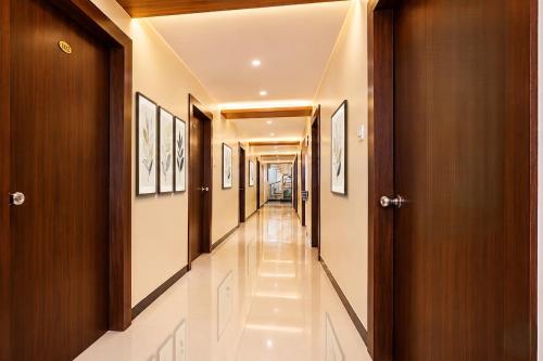 a hallway with white tile floors and wooden doors at FabHotel SK Galaxy in Thane