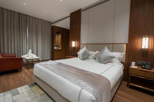 a bedroom with a large white bed and a chair at Park Central Hotel in Ahmadnagar