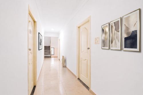 a hallway with white walls and paintings on the walls at FabHotel Ateethi Residency in Pune