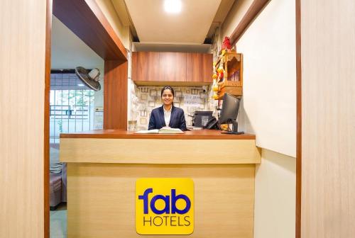 a man is sitting at a reception desk at FabHotel Ateethi Residency in Pune