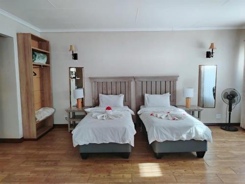 a bedroom with two beds with white sheets and a mirror at TAG@12A in Piet Retief