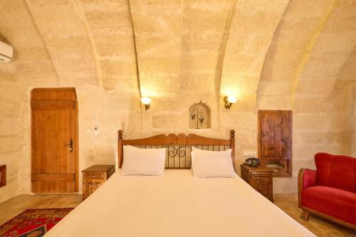 a bedroom with a large bed and a red chair at Mithra Cave Cappadocia in Göreme