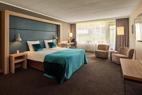 ein Hotelzimmer mit einem großen Bett und einem Stuhl in der Unterkunft Van der Valk Hotel Leusden - Amersfoort in Leusden