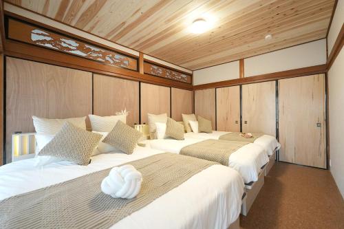 two beds in a room with wooden walls at The CATAN 宮津 in Yura