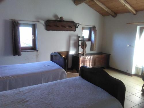 a bedroom with two beds and a desk and windows at La Sereta in Busalla