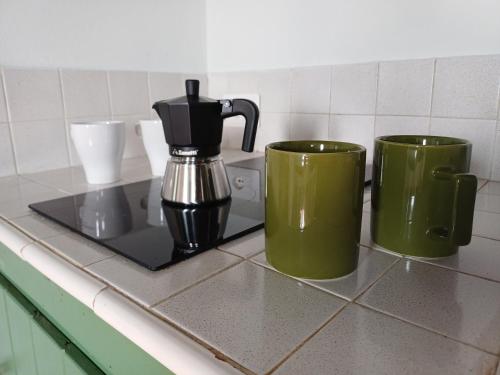 three green coffee mugs sitting on a counter at Calice dei Cherubini in Montecalvo Versiggia