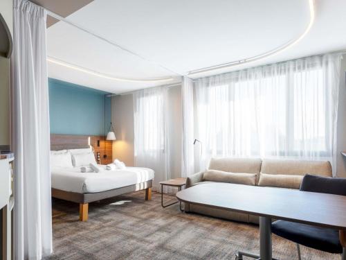 a hotel room with a bed and a couch at Novotel Suites Nancy Centre in Nancy