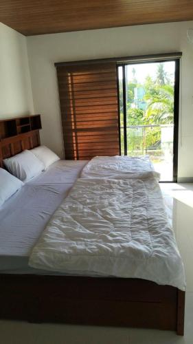 a large bed in a bedroom with a large window at Triple J Villa Puerto Galera in Puerto Galera