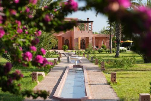 a building with a pond in front of a garden at Domaine 3 Riads in Marrakesh