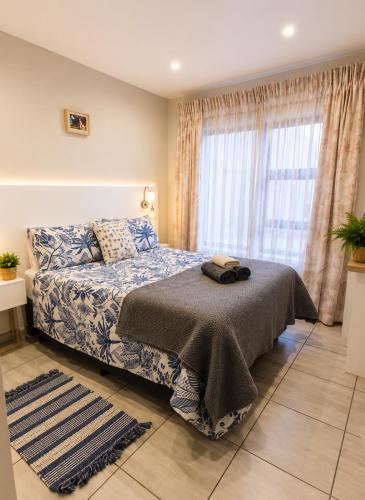 a bedroom with a bed and a large window at Villa Dubaai in Mossel Bay