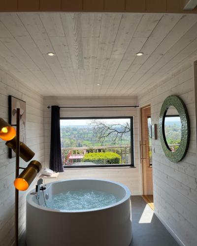 a bath tub in a bathroom with a large window at Domaine de Meros in Plonévez-du-Faou