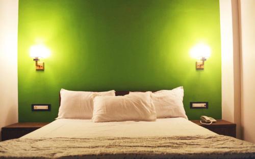 una parete verde con un letto con due luci sopra di Nirvana Inn a Mahabaleshwar