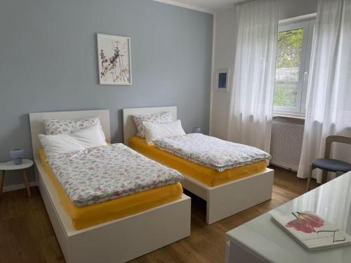 a bedroom with two beds and a table and a window at Petit Fleur in Marktleuthen