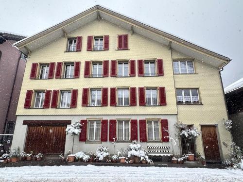 a large yellow house with red shutters in the snow at Little Flowerpot in Unterseen