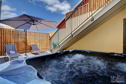 a swimming pool with two chairs and an umbrella at PAPANG - House 148m 3rooms Jacuzzi in Saint-Leu