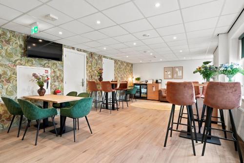 a waiting room with tables and chairs and a kitchen at Guesthouse Ouddorp Connection in Ouddorp