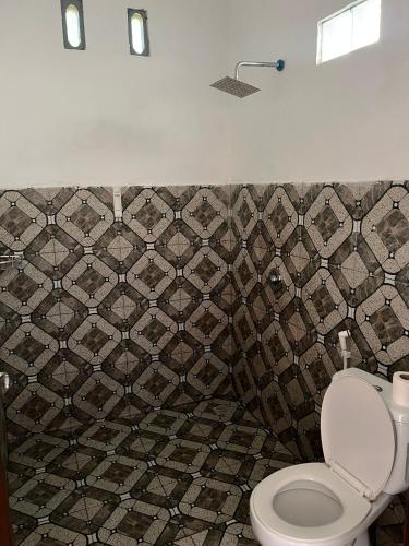 a bathroom with a toilet and a tiled wall at Tetebatu Fullmoon in Tetebatu