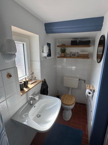 a bathroom with a white sink and a toilet at Dat Lütte Huus - Ferienhaus nahe Greetsiel in Krummhörn